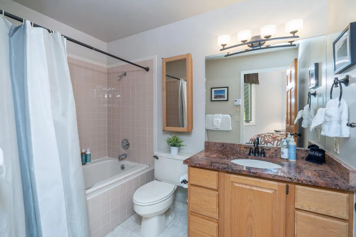 A bright, inviting bathroom featuring a bathtub perfect for a relaxing soak, a sleek vanity with a sink, a well-lit mirror, and elegant lighting. The space is styled for comfort, offering a spa-like ambiance ideal for unwinding after a day of adventure.