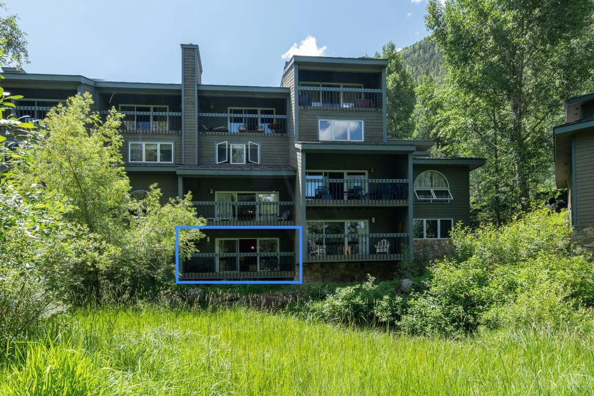 The exterior of the condo building is surrounded by lush greenery, with private balconies overlooking scenic views. The setting invites outdoor relaxation and connects directly to trails and nature.